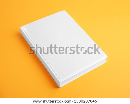 Book with blank cover on yellow background