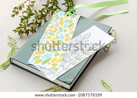 Book with bookmarks, stationery and branch on light background
