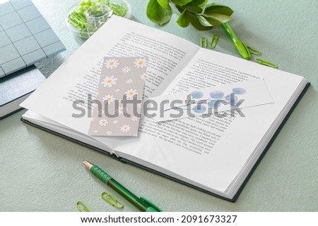 Book with bookmarks and stationery on color background