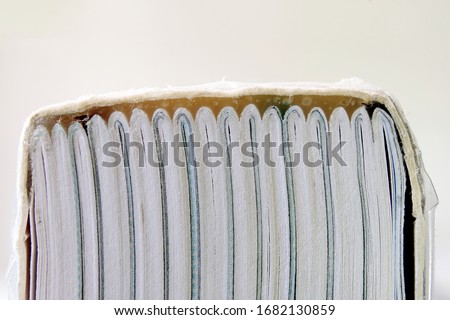A book bound using perfect binding showing the spine and glue holding folded sections of the book together. Pages of a book glued together with the cover using a strong adhesive. Closeup macro view.