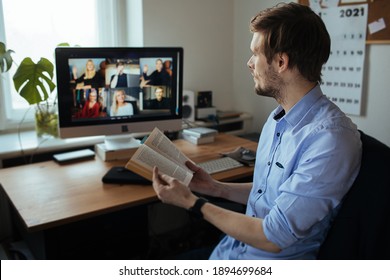 Book Club Online. Handsome young man in casual clothes reading a book in a video conference call  Boring group video chat  While Practicing Social Distancing. Online education video conferencing  - Shutterstock ID 1894699684