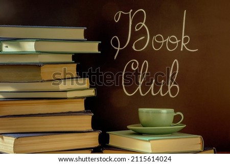 Book Club, toned image. A stack of books with a cup of coffee and chalk lettering on a blackboard