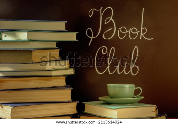 Book Club, toned image. A stack\
of books with a cup of coffee and chalk lettering on a\
blackboard