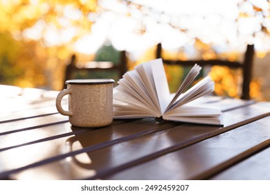 Book and coffee. Autumn reading outdoors. Cup of tea on wooden table in forest. Slow living in cozy authentic garden, mental health, fall vibes and aesthetics. Self-development, education in nature - Powered by Shutterstock