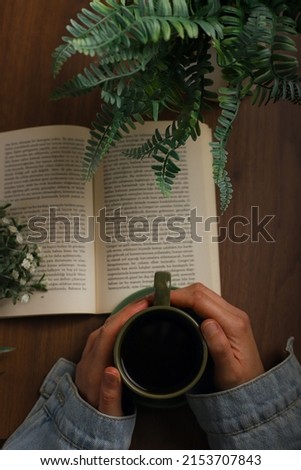 Book and coffee on wooden background. Novel and coffee pleasure in greenery. The perfect combination of book and coffee