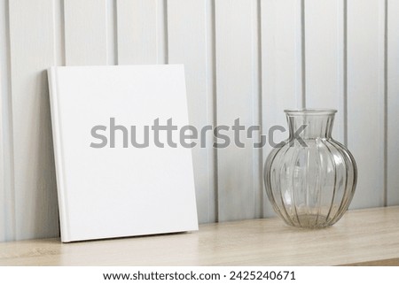 a book with an empty white cover and a vase for flowers. mockup album, copy space. creator of the summer scene in the cottage.
