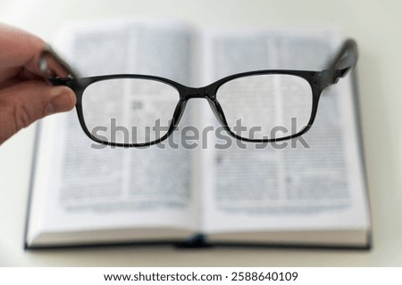 book and eye glasses for read and write over blurred background with copy space, selective focus. reading glasses in his hands on a blurry book background. poor vision concept.