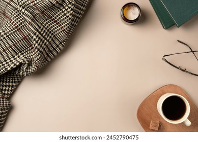 Book, glasses, candle, plaid, with cup coffee on beige background. Leisure concept, reading a book. Flat lay, top view