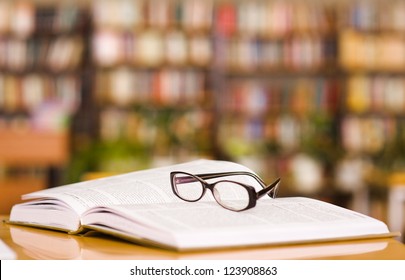 book and glasses on table in library - Shutterstock ID 123908863