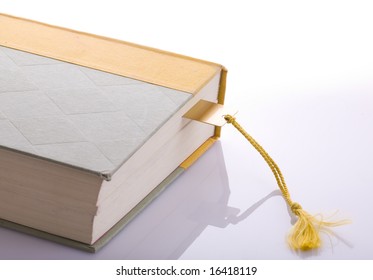 A Book With A Gold Bookmark With A Tassel On A Background.