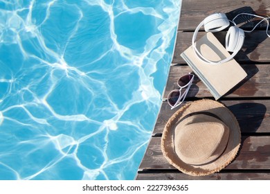 Book and headphones near swimming pool. Summer vacation. Flat lay with copy space - Powered by Shutterstock