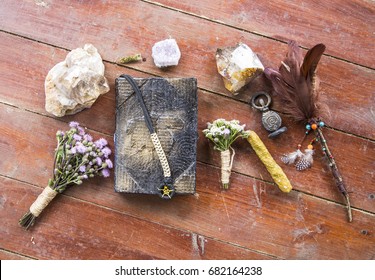 Book of incantations, grimoire, dried flowers, thistle, wand of feathers, quartzite crystal and candles made from natural wax, witchcraft, spells, magic, Wicca, goddess