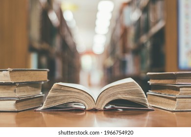 Book in library with old open textbook, stack piles of literature text archive on reading desk, and aisle of bookshelves in school study class room background for academic education learning concept - Shutterstock ID 1966754920