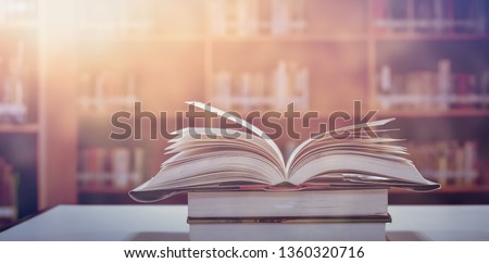 Book in library with old open textbook, stack piles of literature text archive on reading desk, and aisle of bookshelves in school study class room background for academic education learning concept