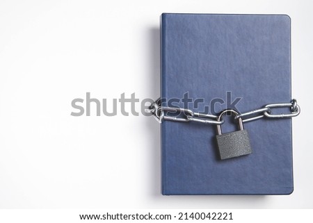 The book is locked under lock and key on a white background. Secret archive. Chain on the book close-up. The book of secrets is under lock and key.