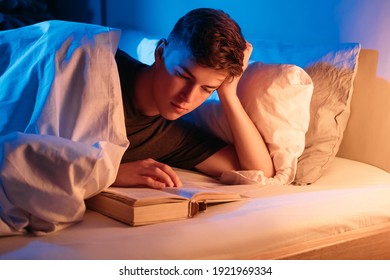 Book Lover. Sleep Disorder. Distance Education. Interesting Story. Overwork Insomnia. Hobby Leisure. Man Reading Laying In Bed At Night Dark Bedroom Interior.