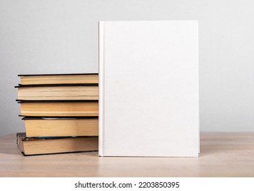 Book Mockup And Novels Stack At Wooden Table. Template With White Blank Cover. Literature, Education, Reading Concept. Advertisement Of New Volume. High Quality Photo