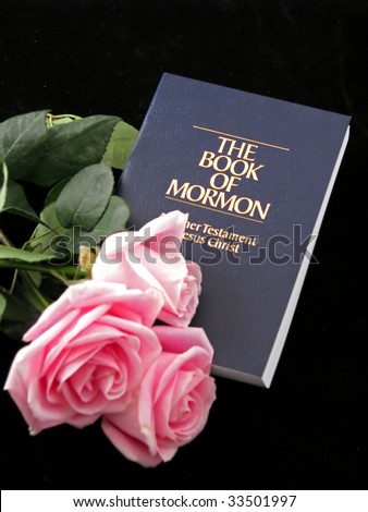 the book of Mormon and three pink roses on black background