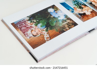 A Book With New Year Photos Of Big Family At Home On A White Background. Photobook Is Gift. Professional Photographer And Designer. Printing Of Photos And Journals In Photo Laboratory