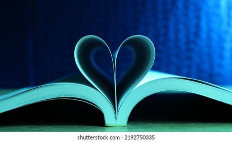 The book on the table was opened in the middle and folded into a heart shape. with a dark blue background Represents a symbol of steadfast love.