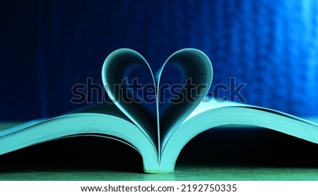 The book on the table was opened in the middle and folded into a heart shape. with a dark blue background Represents a symbol of steadfast love.