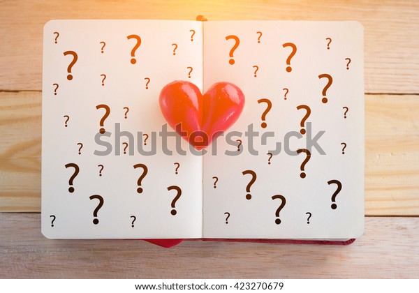 Book with opened pages and clay heart with question mark symbol love concept