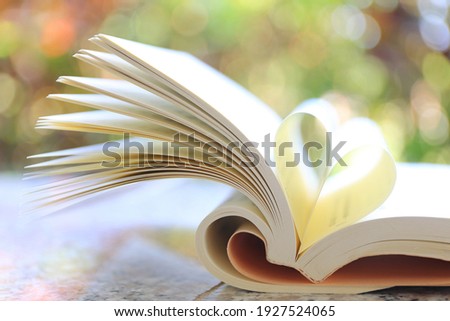 The book opens, and the book page rolls into the heart colorful background selective focus and with a very shallow depth of field 
