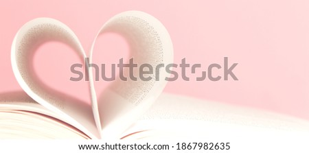 Book pages in shape of heart on pink background. Love, valentines or mother's day concept. Close up, copy space.