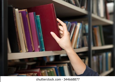 a book picked or taken with a hand from a book shelf in the library, a concept of learning and choice