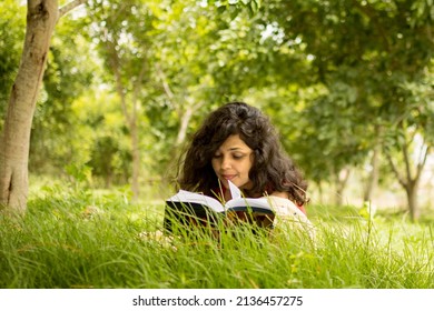 A Book Reading Girl - A Cute Indian Girl Reading Book Lying On Grass Outdoor In Nature. 