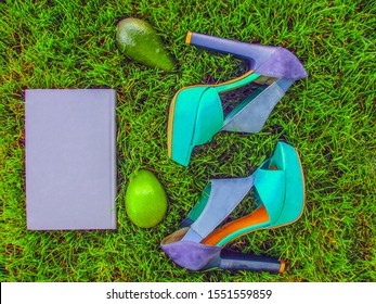 Book, Sandals Laying On Green Grass. Lifestyle Objects In Flat Lay Top View Arrangement, Overhead View