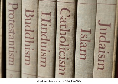 Book spines listing major world religions    Judaism  Islam  Catholicism  Hinduism  Buddhism   Protestantism  The focus is the word  Catholicism 