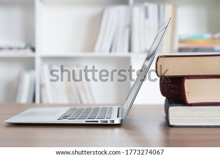 book stack and laptop on desk in library. education technology and e-learning class concept.