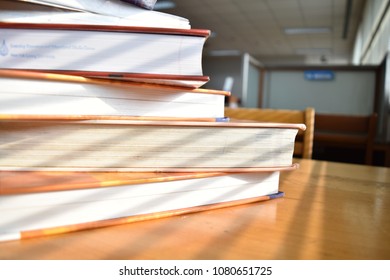 book stack on desk with sunlight from window in library
