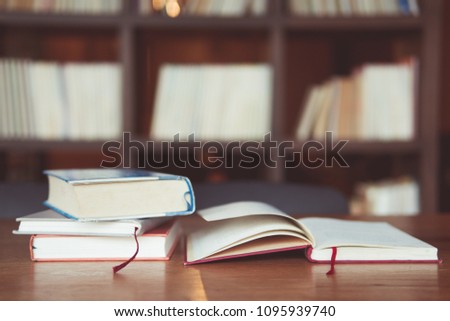 Book stack on Wood table with book shelf is background at library room with Copy space concetp.