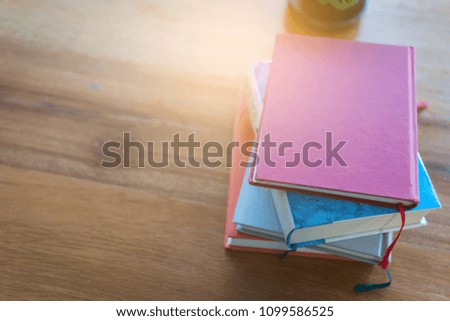 Book stack on Wood table with book shelf is background at library room with Copy space concetp.