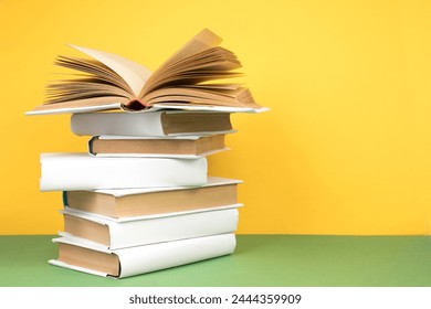 Book stacking. Open hardback books on wooden table and green background. Back to school. Copy space for ad text - Powered by Shutterstock