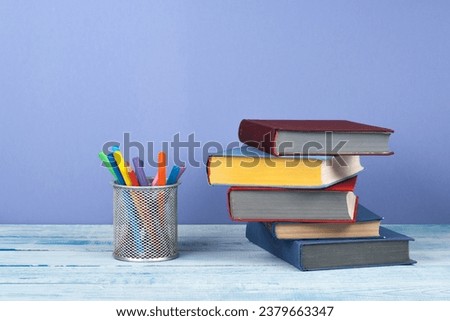 Book stacking. Open book, hardback books on wooden table and blue background. Back to school. Copy space for text
