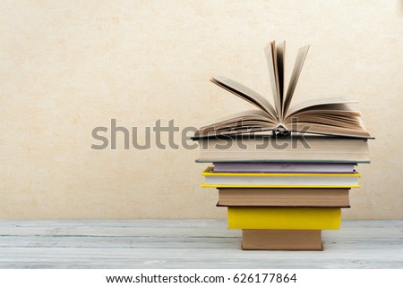 Book stacking. Open book, hardback books on wooden table and blue background. Back to school. Copy space for text