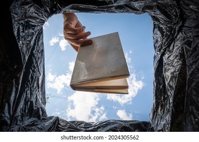 Book that do not read, low-grade literature. A stupid, uneducated man throws his textbook in the trash. The concept of bad education. Digitalization and e-books. Unnecessary reading.