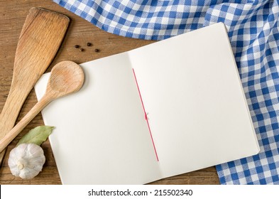 Book with wooden spoons on a blue checkered tablecloth