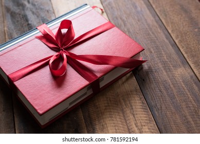 Book Wrapped With Ribbon As A Gift. Book On Wooden Table