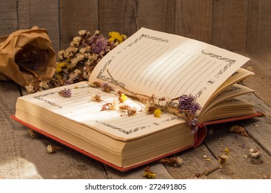 Book to write notes with dried flowers, herbs on wooden background. Soft focus, deliberate slight blurring .