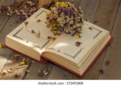 Book to write notes with dried flowers, herbs on wooden background.