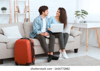 Booking Tour. Happy Couple Using Laptop At Home And Preparing For Travel