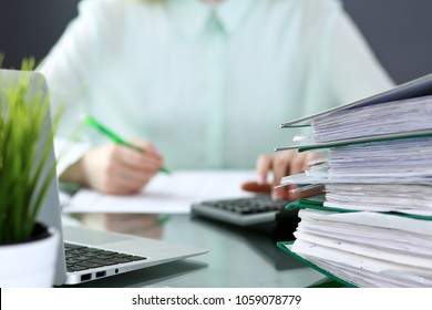 Bookkeeper or financial inspector  making report, calculating or checking balance. Binders with papers closeup. Audit and tax service concept. Green colored image background  - Shutterstock ID 1059078779