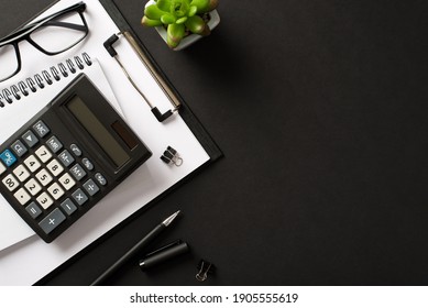 Bookkeepers work place concept. Top above overhead view photo of office accessories calculator pen clipboard notebook isolated black color backdrop with blank empty space - Shutterstock ID 1905555619