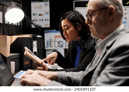 Bookkeeping business executives coworkers imputing administrative analytics data on laptop. Teamworking elderly businessman and asian collegue in accountancy archival depository storage office
