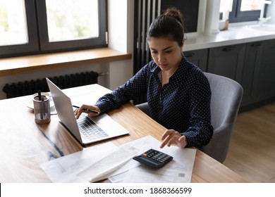 Bookkeeping  Busy millennial indian woman professional accountant preparing annual financial report checking result calculator  Mixed race female freelancer counting tax rates declaring income