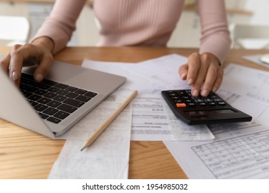 Bookkeeping requires accuracy. Young woman hands typing on computer and digital calculator keyboards preparing electronic payments of utility bills counting taxes sum balancing accounts. Close up view - Shutterstock ID 1954985032